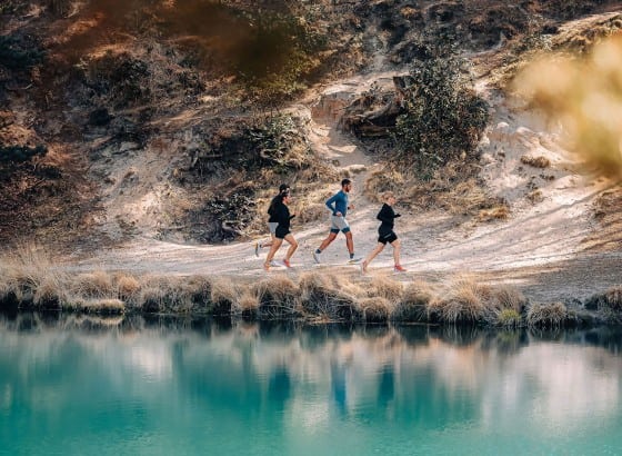 Running group training along scenic trail near water, outdoor running, fitness, endurance building, trail running tips, running insights for performance improvement.