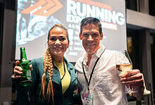 Energetic runners at the Running Insights event, networking and celebrating running achievements with drinks, in a lively indoor setting.