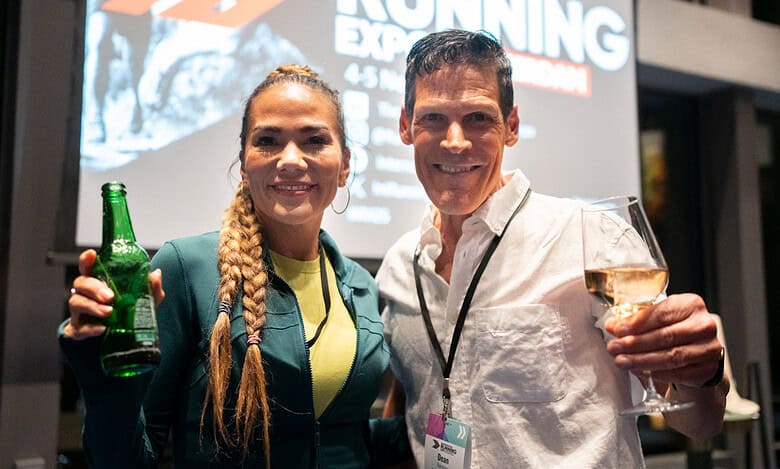 Energetic runners at the Running Insights event, networking and celebrating running achievements with drinks, in a lively indoor setting.
