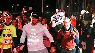 Brightly lit marathon finish line with runners and supporters, showcasing dedication and celebration at night, emphasising performance and sportsmanship in running events.