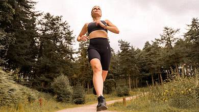 Female runner in black sportswear running on forest trail, outdoor running, fitness training, trail running, athletic performance, endurance, healthy lifestyle, Running Insights.