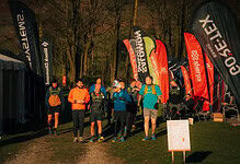 Energetic trail runners gathering at a night race event, showcasing running gear and hydration as they prepare for a marathon in the woods.