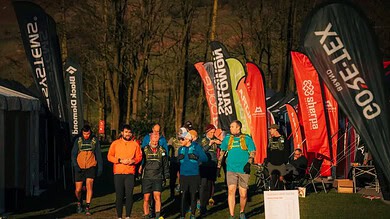 Energetic trail runners gathering at a night race event, showcasing running gear and hydration as they prepare for a marathon in the woods.