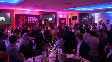 Running industry awards ceremony with attendees in formal attire, stage setup, and vibrant lighting, celebrating achievements in the running and athletics community.