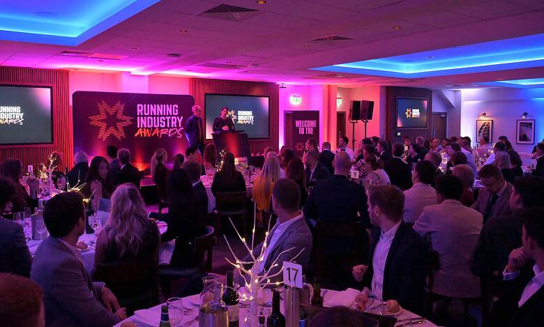 Running industry awards ceremony with attendees in formal attire, stage setup, and vibrant lighting, celebrating achievements in the running and athletics community.