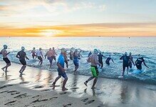 A group of athletes participating in an open water swim race at sunrise, demonstrating endurance and outdoor fitness.