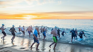 A group of athletes participating in an open water swim race at sunrise, demonstrating endurance and outdoor fitness.