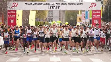 Marathon runners at the starting line of the Mezza Maratona d’Italia, Enzo Ferrari Memorial, ready to begin the race. The image captures a diverse group of athletes in motion, emphasizing endurance an.