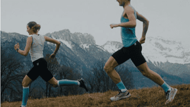 An image of a man and a girl running outdoors on a trail with mountain scenery in the background, highlighting trail running and outdoor fitness.
