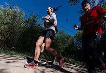 Female runner Sarah Perry finishing the Legends race, showcasing endurance and determination on a sunny trail.