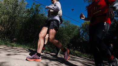 Female runner Sarah Perry finishing the Legends race, showcasing endurance and determination on a sunny trail.