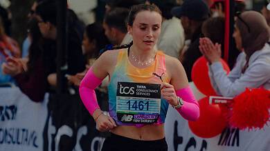 Female marathon runner in race, wearing pink arm sleeves and running shoes, with bib number 1461, competing in a city marathon event.
