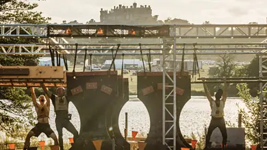 Outdoor fitness training with athletes on stage at a scenic lakeside location.