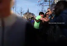 Group of runners and spectators at a running event, with ASICS branding and a motivational slogan, capturing the energy and community spirit of running.
