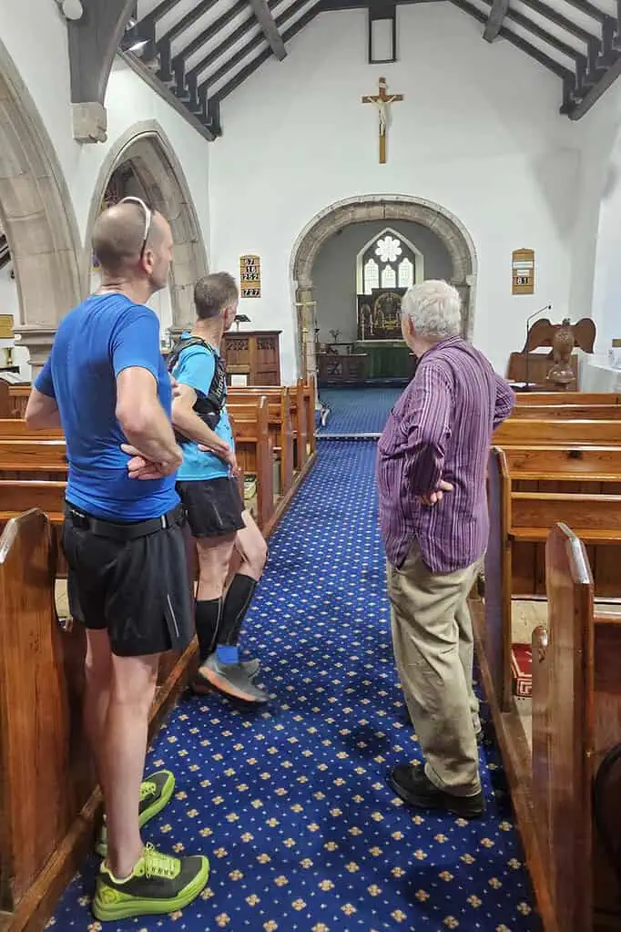 Running Insights, running club members receiving coaching inside a church, with a priest present, during a community event focused on running and faith.