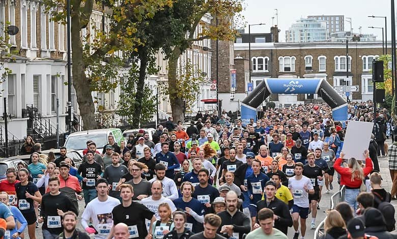 Large group of runners participating in the Stockport 10K race, with an archway and cityscape in the background.