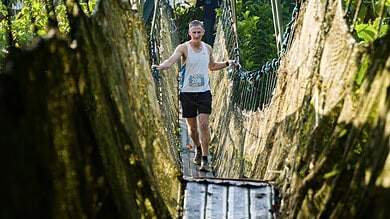 Runner crossing a narrow suspension bridge in a forest