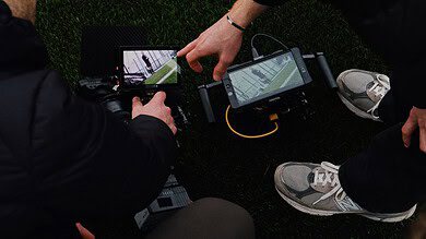 Two runners reviewing running data on a smartphone and GPS device during a training session.