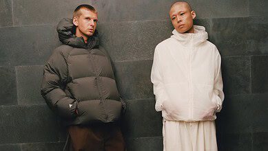 Two models wearing winter outerwear from adidas and Arte Antwerp's FW26 collection, standing against a dark wall.