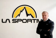 Man standing confidently with arms crossed in front of La Sportiva logo, showcasing outdoor sports and running gear expertise.