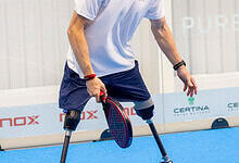 Male athlete with prosthetic legs practicing adaptive sports on a blue indoor court, demonstrating resilience and determination.