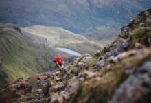 Trail runner in a red jacket crossing rocky Welsh mountain terrain in an illustrative Dragon's Back Race photograph, not Ultra X South Africa