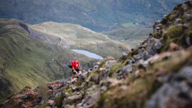 Trail runner in a red jacket crossing rocky Welsh mountain terrain in an illustrative Dragon's Back Race photograph, not Ultra X South Africa